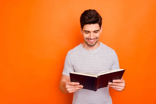 Fénykép vicces vonzó srác tartsa kedvenc könyv kezét élvezze olvasás izgalmas végső intrika kopás csíkos póló elszigetelt fényes narancs színű háttér — Stock Fotó