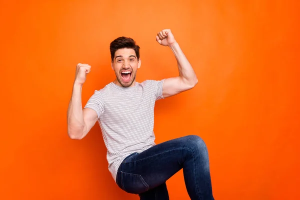 Photo of crazy funky guy yelling loud open mouth raise fists sportive cheerleader rejoicing best win team wear casual striped t-shirt jeans isolated bright orange color background — ストック写真