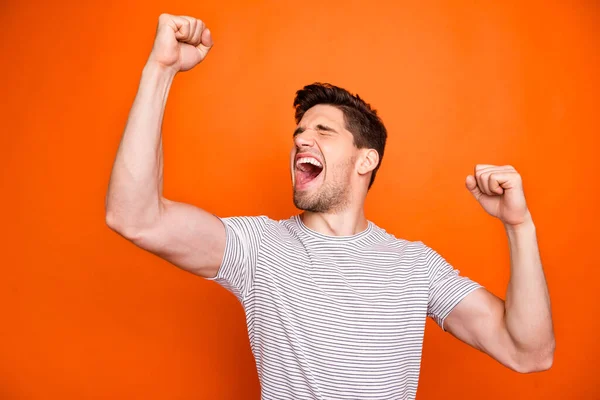 Photo of crazy funky guy yelling loud open mouth best feelings raise fists eyes closed cheerleader rejoicing wear casual striped t-shirt isolated bright orange color background — 스톡 사진