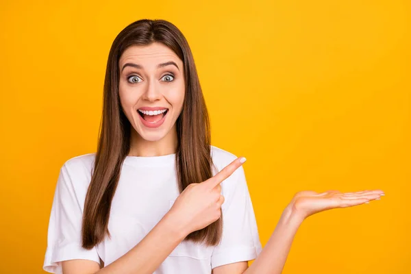 Foto de senhora de negócios bonita boca aberta dedo direto espaço vazio na palma aberta segurar novidade vender produto desgaste casual branco t-shirt isolado vívido cor amarela fundo — Fotografia de Stock