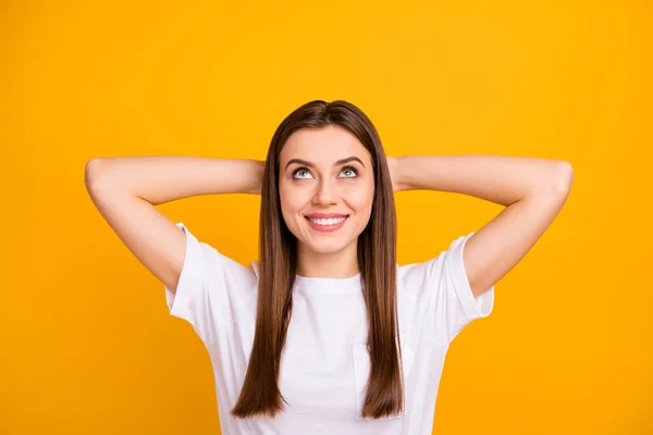 Closeup photo of pretty calm lady good mood thinking looking up empty space arms behind head delighted toothy wear casual white t-shirt isolated vivid yellow color background — 图库照片
