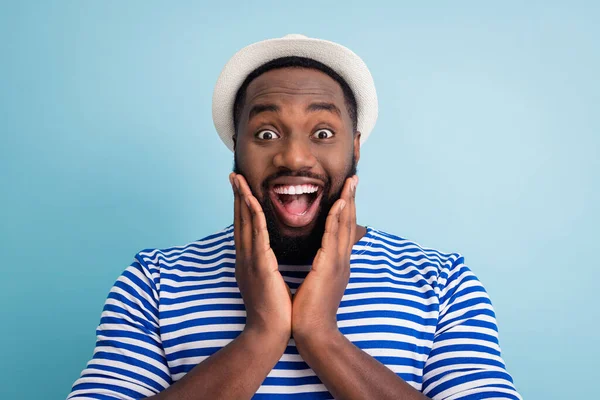 Cool. Closeup photo of crazy funky dark skin guy rest resort see shopping center prices open mouth arms on cheekbones wear white sun cap striped sailor shirt isolated blue color background — Stok fotoğraf