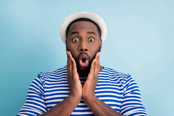 Closeup photo of crazy dark skin guy rest abroad resort see shopping center prices open mouth arms on cheeks wear white sun cap striped sailor shirt isolated blue color background — Stockfoto