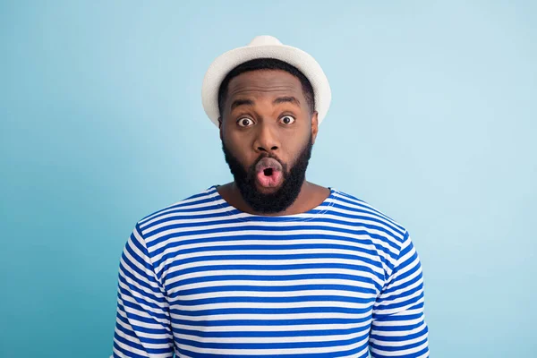 Photo of funny dark skin guy rest abroad spend free time resort see low shopping center prices open mouth wear white sun cap striped sailor shirt isolated blue color background — Stock fotografie