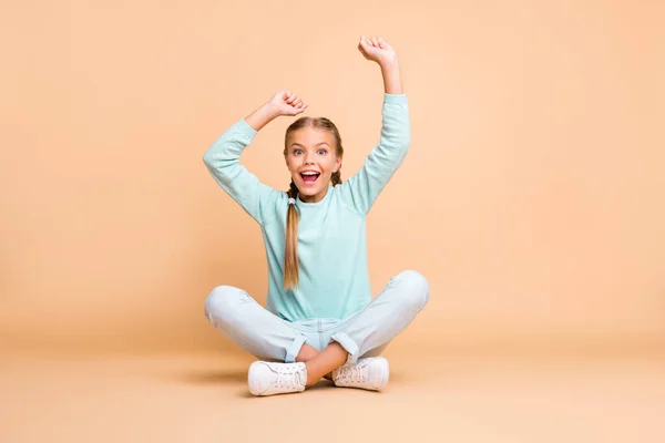 Goal. Full body photo of beautiful little lady raise fists watching sport match excited fan sit floor legs crossed wear blue sweater jeans footwear isolated beige color background — Stok fotoğraf