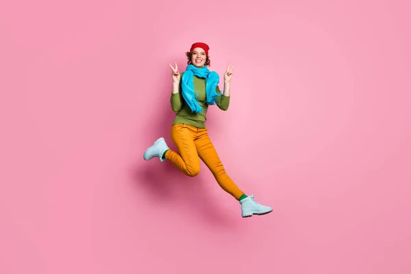 Foto de tamaño completo de alegre salto chica bonita disfrutar de vacaciones fin de semana de otoño tiempo libre hacer v-signos de desgaste estilo casual pantalones de moda ropa zapatos aislados sobre fondo de color rosa —  Fotos de Stock