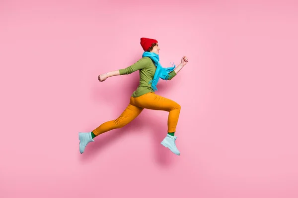 Full size profile side photo of cheerful charming girl jump up run after spring time discounts wear shoes red blue sweater pants headwear isolated over pink color background — Stockfoto