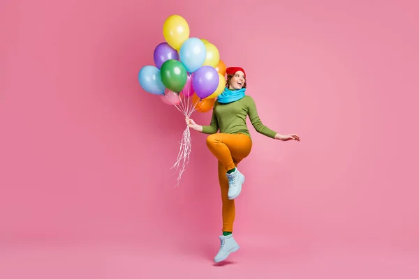 Full length photo of cheerful millennial girl jump hold many air helium balloons look copyspace enjoy winter festive anniversary wear footwear pants isolated over pink color background — Stockfoto