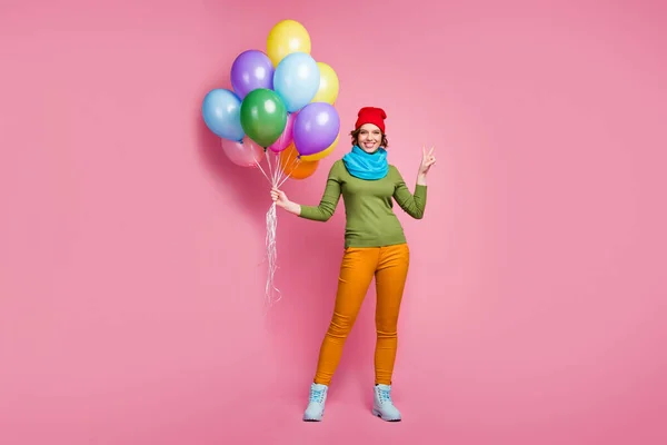 Foto de cuerpo completo de chica alegre celebrar muchos globos de aire hacen v-signo disfrutar de otoño aniversario ocasión desgaste estilo casual pantalones de jersey calzado aislado sobre fondo de color rosa — Foto de Stock