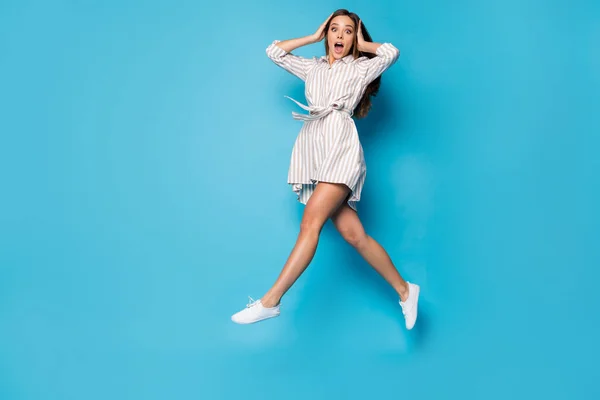 Full length profile photo of funny crazy lady jump high shopping center sale prices addicted shopper open mouth wear spring striped mini dress footwear isolated blue color background — Stockfoto