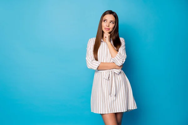 Photo of pretty attractive lady good mood hold hand on chin intelligent person look side up empty space interested wear striped casual summer short dress isolated blue color background — ストック写真