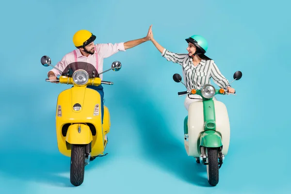 Full size photo of funny two people lady guy drive retro moped one team travelers good mood clap arms formalwear clothes protective caps isolated blue color background — Stock Fotó