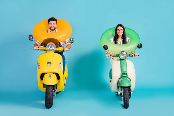 Full body photo of funky two people lady guy drive retro moped good mood hold colorful life buoys travelers resort vacation formalwear clothes isolated blue color background — Stockfoto