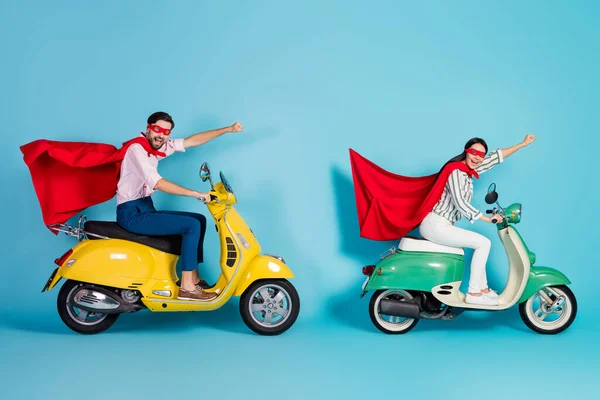 Full length profile photo of crazy lady guy drive two retro moped raise fists wear red cape cloak mask rushing road party super heroes role coat fly air isolated blue color background — Zdjęcie stockowe
