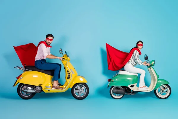 Full size photo of crazy excited lady guy drive two vintage moped wear red cape mask rushing road party play super heroes role coat flying air isolated blue color background — Zdjęcie stockowe