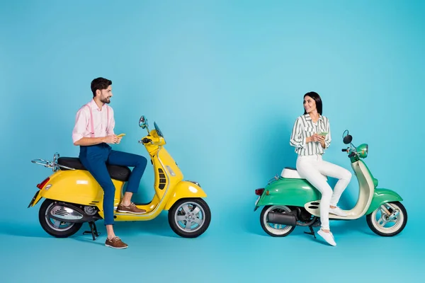 Full body profile photo of funny lady guy two people driving two vintage moped together browsing telephone affectionate feelings formalwear outfit isolated blue color background — Stock fotografie