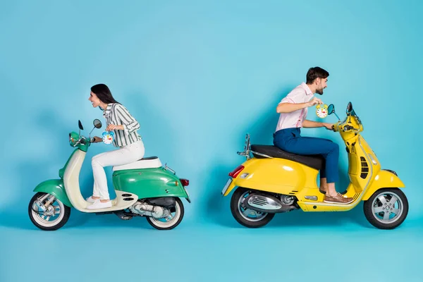 Full length profile side photo crazy two people biker hold clock ride fast road route dont want overtime yellow green motor bike party wear formalwear shirt pants isolated blue color background — ストック写真