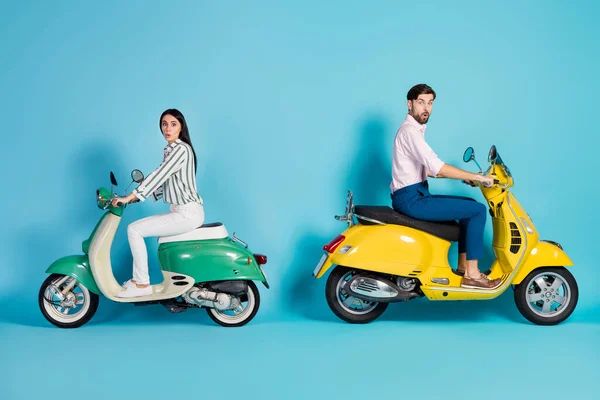 Full length profile side photo of shocked two people man woman ride motor bike impressed by high fast speed scream wow omg wear shirt white pants trousers isolated over blue color background — Stockfoto
