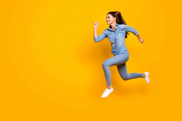 Full body profile photo of pretty funky lady jump high up rejoicing good mood rushing speed running final wear casual denim outfit white footwear isolated yellow color background — Stockfoto