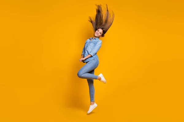 Full length profile photo of pretty lady jumping high up hairdo flying good mood weekend wear casual jeans denim outfit white shoes isolated yellow color background — ストック写真