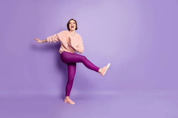 Teljes méretű fotó csinos hölgy tánc furcsa modern mozog disco party diákok hűtés emelje fel az egyik lábát izgatott viselni alkalmi elegáns pulóver nadrág elszigetelt lila szín háttér — Stock Fotó