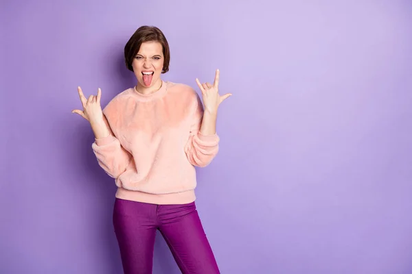 Photo of crazy funky lady rocker soul sticking tongue out mouth showing hands horns metal rock concert wear casual stylish pullover pants isolated purple color background — Stock Photo, Image