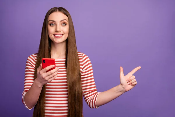 Portrait of positive confident girl promoter use smartphone indicate social network adverts promo point index finger copyspace wear sweater isolated over purple color background — 图库照片
