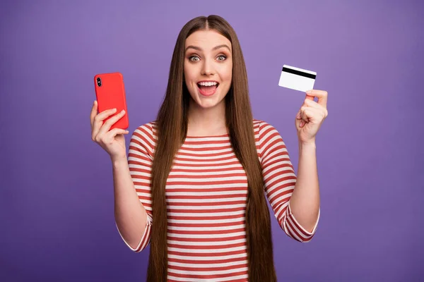 Emocionado chica loca uso teléfono inteligente impresionado fácil pago bancario en línea con tarjeta de crédito gritar wow omg desgaste suéter de rayas blancas aislado color violeta fondo —  Fotos de Stock