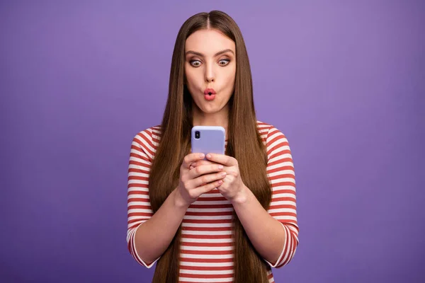 Bilde av attraktiv, sjokkert dame - se på åpen munn - telefonskjerm les negative kommentarer - nytt blogginnlegg - kle stripete skjorte - isolert pastellfarget lilla bakgrunn – stockfoto