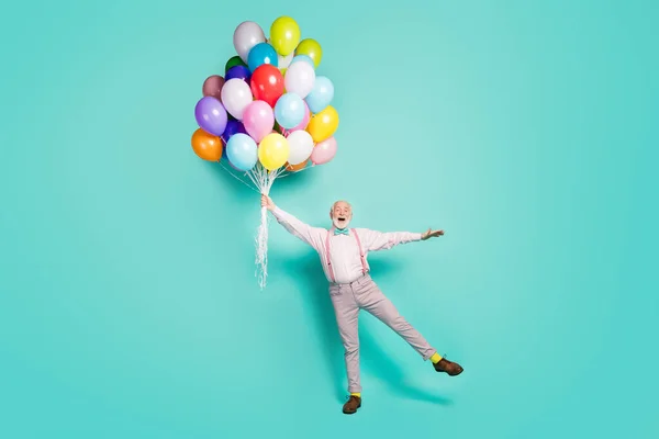 Full size photo excited amazed grey white bearded old man hold balloons flying wind in sky impressed scream wow omg wear pink pants trousers footwear bowtie isolated turquoise color background — Stockfoto