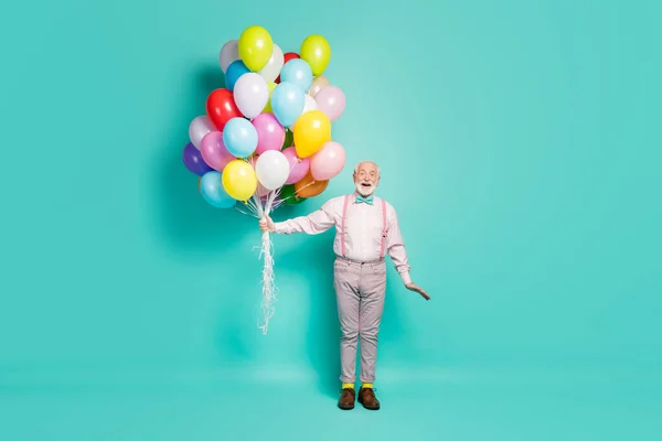 Full body photo of amazed excited old man hold many air balloons enjoy festive anniversary party wear pants trousers brown shoes isolated over turquoise color background — Stockfoto