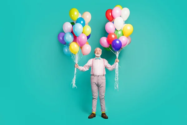 Full size photo of positive cheerful old man hipster hold many air balls enjoy festive occasion event wear good look trousers brown shoes isolated over teal color background — Stockfoto