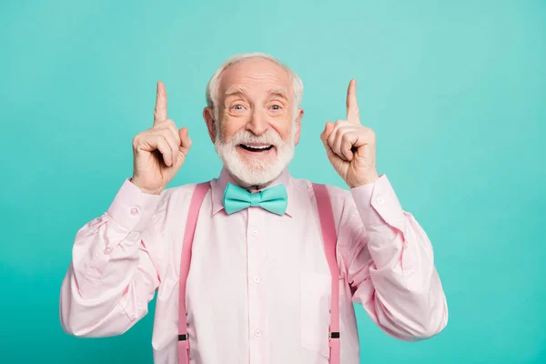 Portrait of amazed excited old man point index finger up recommend suggest select ads promo sales wear pink shirt bowtie isolated over turquoise color background — Stock Fotó