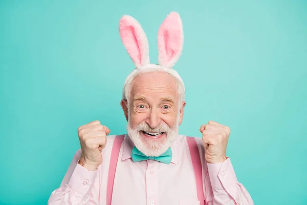 Close up photo of funky excited positive retired gentleman celebrate traditional easter event raise fists enjoy victory wear pink rabbit headband isolated over turquoise color background — Φωτογραφία Αρχείου