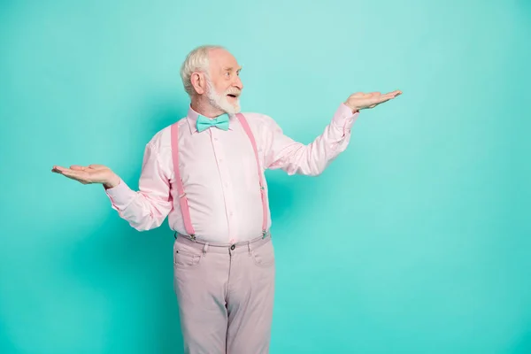 Portrait of surprised shocked old retired man hold hand look adverts promo have choice decisions wear pink pants trousers isolated over turquoise color background — Stok fotoğraf