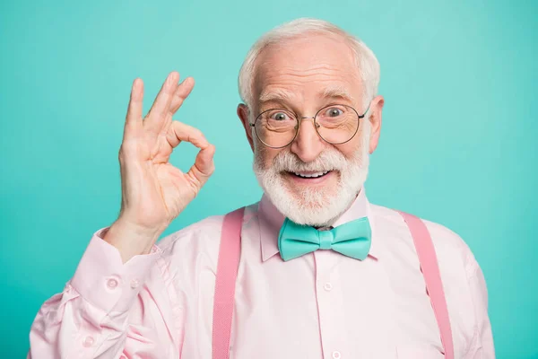 Closeup photo of amazing grey haired grandpa showing okey symbol express agreement wear specs pink shirt suspenders bow tie isolated bright teal color background — Stock Fotó