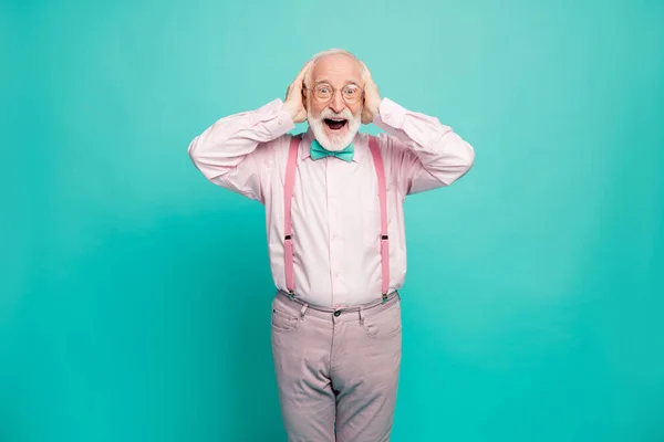 Photo of crazy grandpa positive expression arms on head good mood addicted shopper wear specs pink shirt suspenders bow tie pants isolated bright teal color background — 스톡 사진