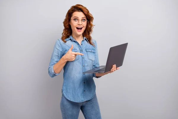 Portrait of surprised astonished woman use laptop search wireless connection indicate ads promotion impressed scream wow omg wear denim jeans shirt isolated over grey color background — Stock Photo, Image