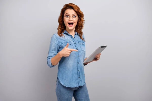 Portrait of surprised woman use tablet search social networking news impressed scream wow omg point index finger wear style stylish trendy denim jeans shirt isolated over grey color background — Zdjęcie stockowe