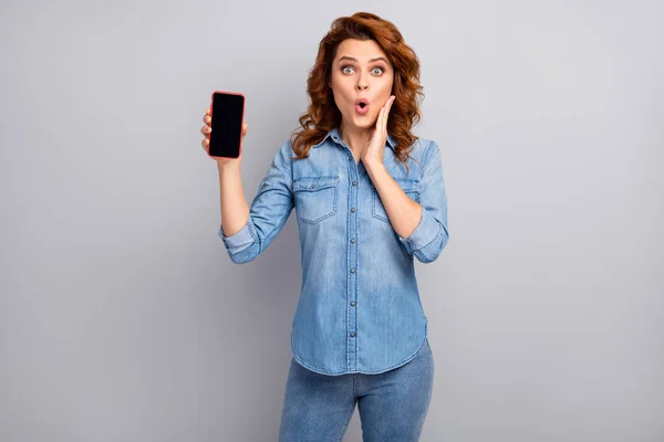 Portrait of astonished crazy woman hold smartphone show new device impressed scream unbelievable unexpected wear good look outfit isolated over grey color background — Stockfoto