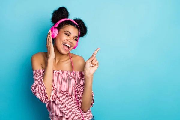 Photo of funky crazy dark skin lady listen music modern earphones sing favorite song raise index finger wear trendy red white striped shirt off-shoulders isolated blue color background — Stockfoto