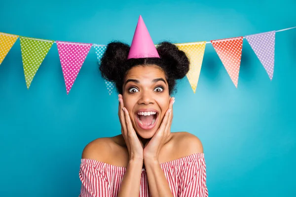 Photo of crazy dark skin lady arms cheekbones unexpected surprise birthday party wear cone cap red white striped shirt naked shoulders colorful dotted flags hang over blue color background — Stockfoto