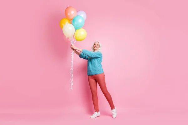 Full size photo of candid satisfied old woman enjoy her grand kid anniversary celebration hold many air helium baloons wear casual style jumper isolated pastel color background — Stockfoto