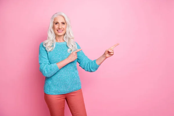 Portrait of positive cheerful old woman promoter point index finger copyspace indicate ads promotion present choice decisions wear jumper isolated over pastel color background — Zdjęcie stockowe