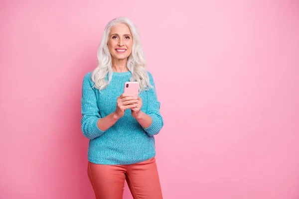 Portrait of positive cheerful modern old woman use cellphone enjoy reading social media post family repost wear casual style blue sweater trousers isolated over pastel color background — Stok fotoğraf