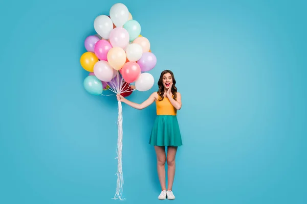 Omg its for me. Full size photo astonished girl get many helium baloons woman day celebration scream touch hands face wear bright short mini singlet footwear isolated blue color background — ストック写真