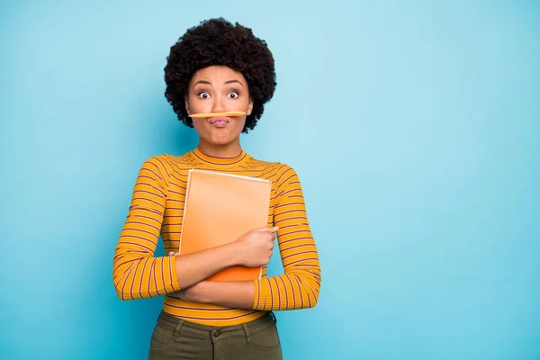 Foto di bella pelle scura ondulato signora tenere copybook dont want studio holding penna su labbra fingendo ragazzo baffi usura giallo camicia a righe pantaloni isolato blu colore sfondo — Foto Stock