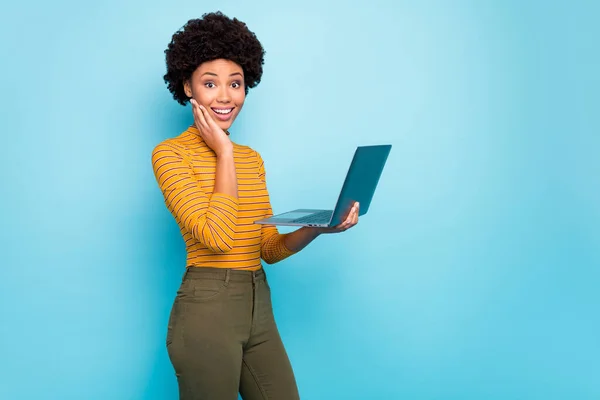 Photo de profil de jolie peau foncée dame bouclée tenir des mains de cahier de lecture de bonnes nouvelles technologie moderne utilisateur porter jaune rayé pull isolé fond de couleur bleue — Photo