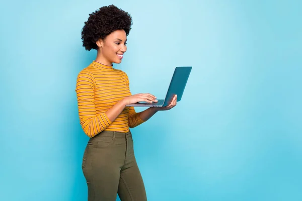 Profile photo of pretty dark skin wavy lady hold notebook hands reading broker service website want to buy apartments wear yellow striped jumper isolated blue color background — Φωτογραφία Αρχείου