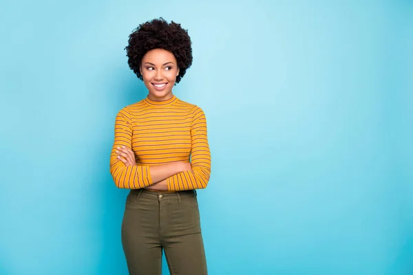 Foto di incredibile divertente pelle scura riccia signora dentino sorridente braccia incrociate cercando lato vuoto spazio indossare casual pullover a righe pantaloni isolato colore blu sfondo — Foto Stock